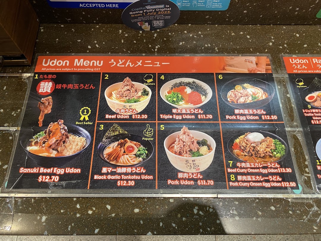 A detailed menu board displaying various udon and ramen dishes with prices and images.