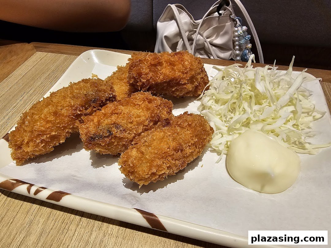 A plate of golden-fried tempura or katsu items with shredded cabbage and mayonnaise.