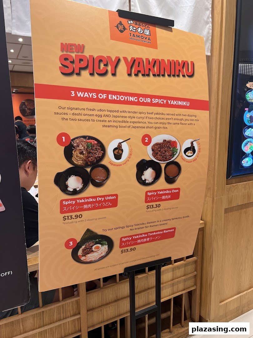 A promotional standee showcasing Tamoya Udon's new 'Spicy Yakiniku' dishes with prices and descriptions.
