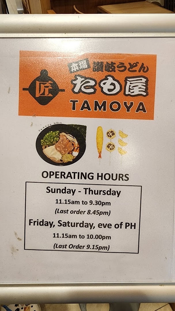 An informational sign for Tamoya Udon, displaying its logo, food illustrations, and detailed operating hours.