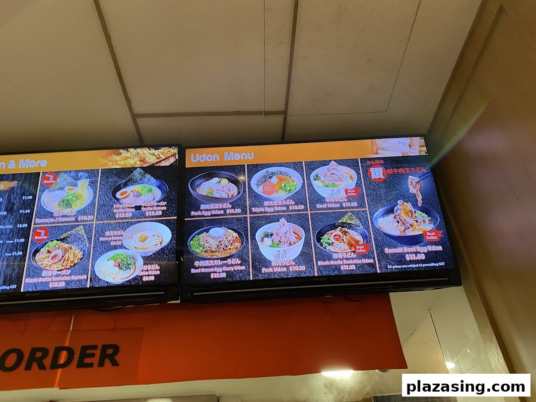 Digital menu boards displaying a variety of Japanese udon and ramen dishes with prices.