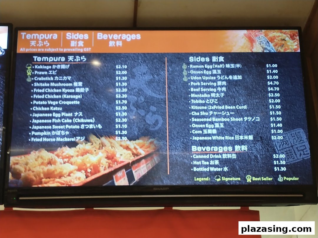 A digital menu board displaying a variety of tempura, sides, and beverages with prices at Tamoya Udon.
