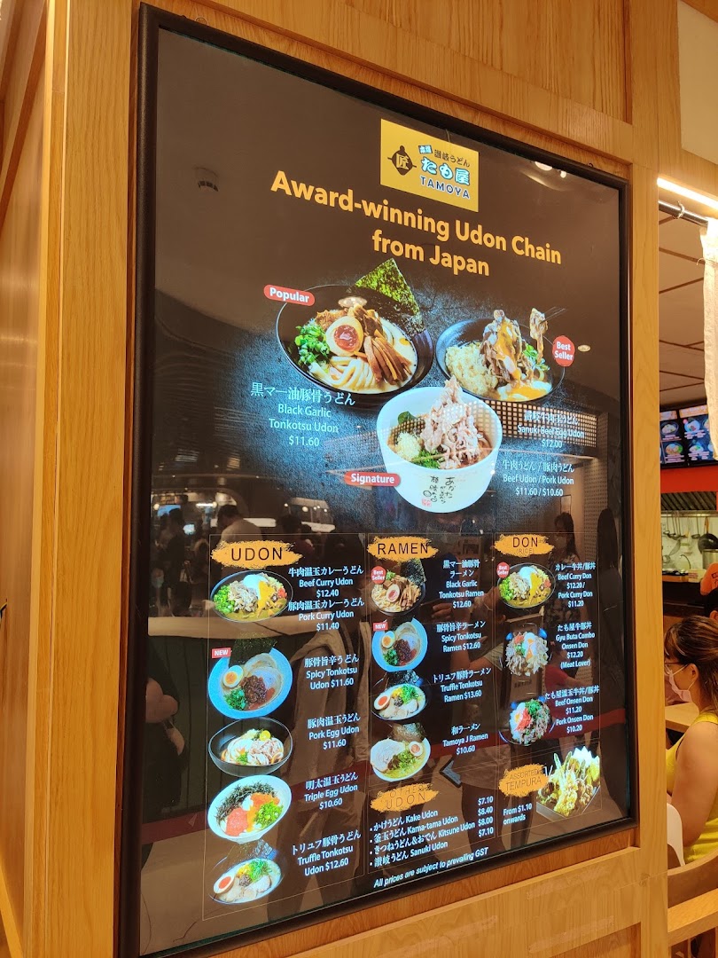 A digital menu board for Tamoya Udon, showcasing various Japanese udon, ramen, and donburi dishes with prices.