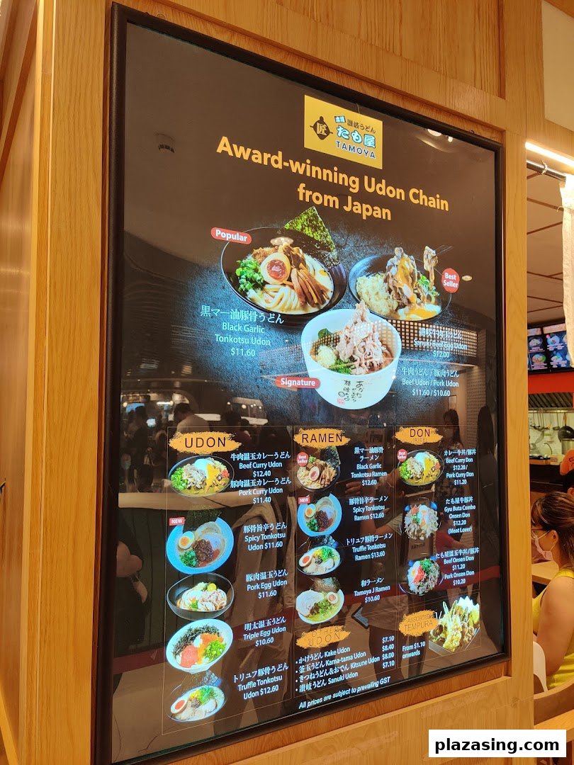 A digital menu board for Tamoya Udon, showcasing various Japanese udon, ramen, and donburi dishes with prices.