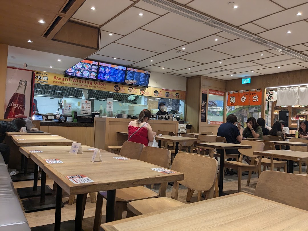 Interior view of Tamoya Udon & Tempura, showing dining area, customers, and kitchen counter.