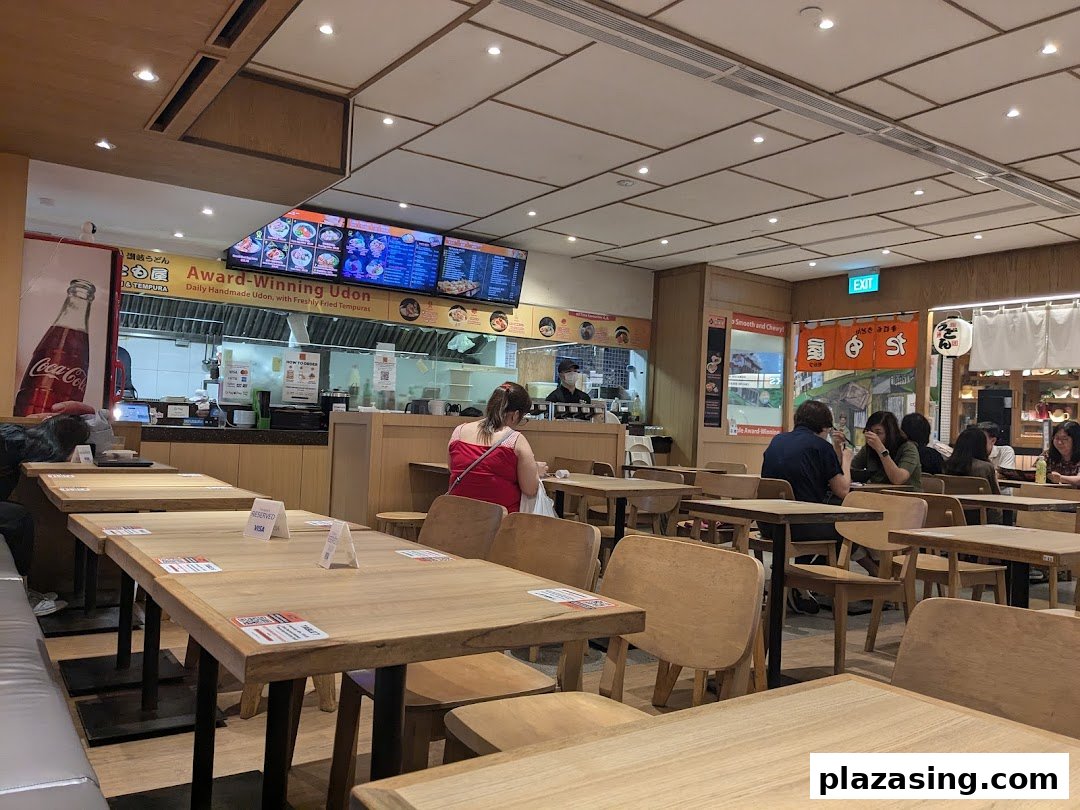 Interior view of Tamoya Udon & Tempura, showing dining area, customers, and kitchen counter.