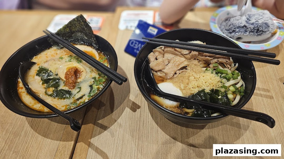 Two bowls of delicious Japanese noodles, one ramen and one udon, served on a wooden table.