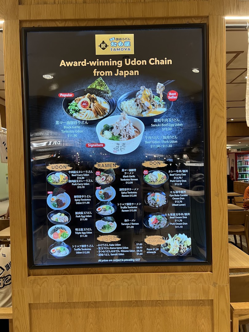 A digital menu board displaying various udon, ramen, donburi, and tempura dishes with prices and images.