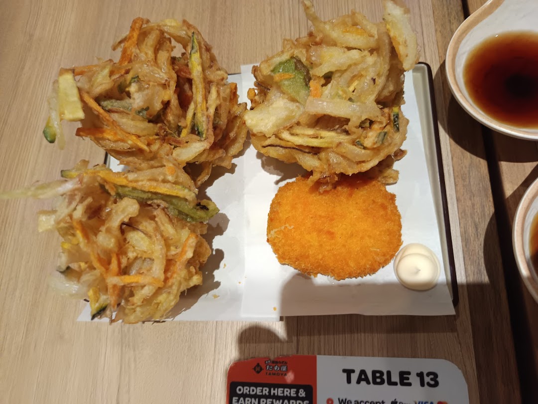 A plate of crispy vegetable tempura and a golden fried croquette with dipping sauces.