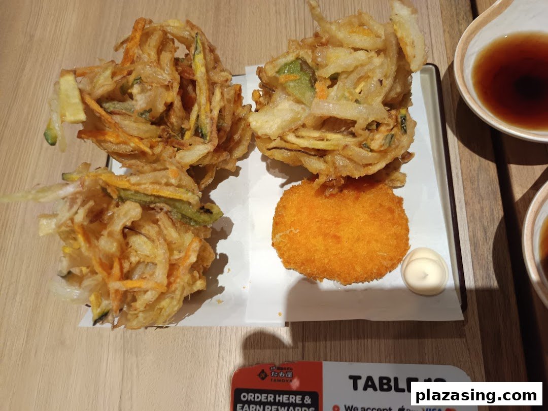 A plate of crispy vegetable tempura and a golden fried croquette with dipping sauces.