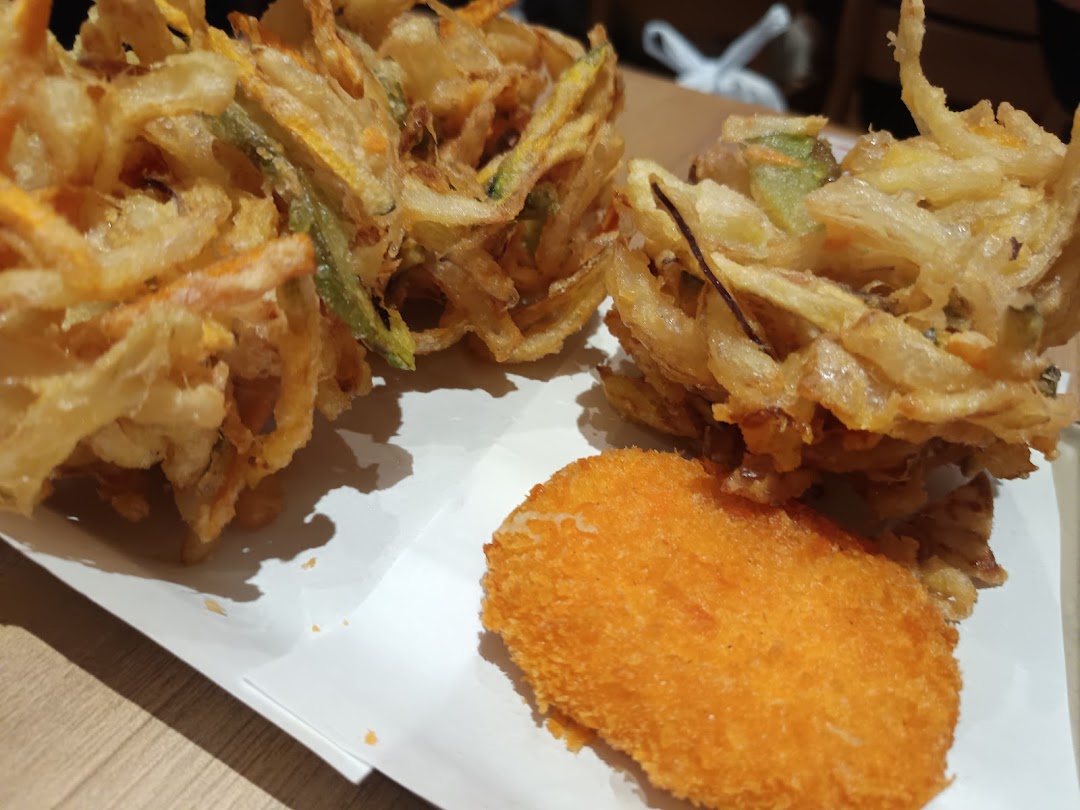 Close-up of crispy Japanese tempura, including kakiage and a breaded item, on a white plate.