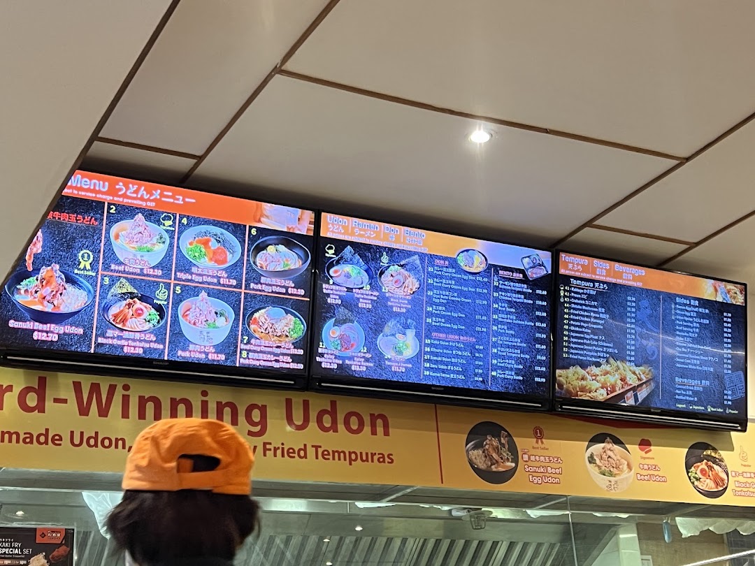 Digital menu boards at Tamoya Udon Tempura, showcasing a variety of udon, ramen, don, tempura, sides, and beverages.