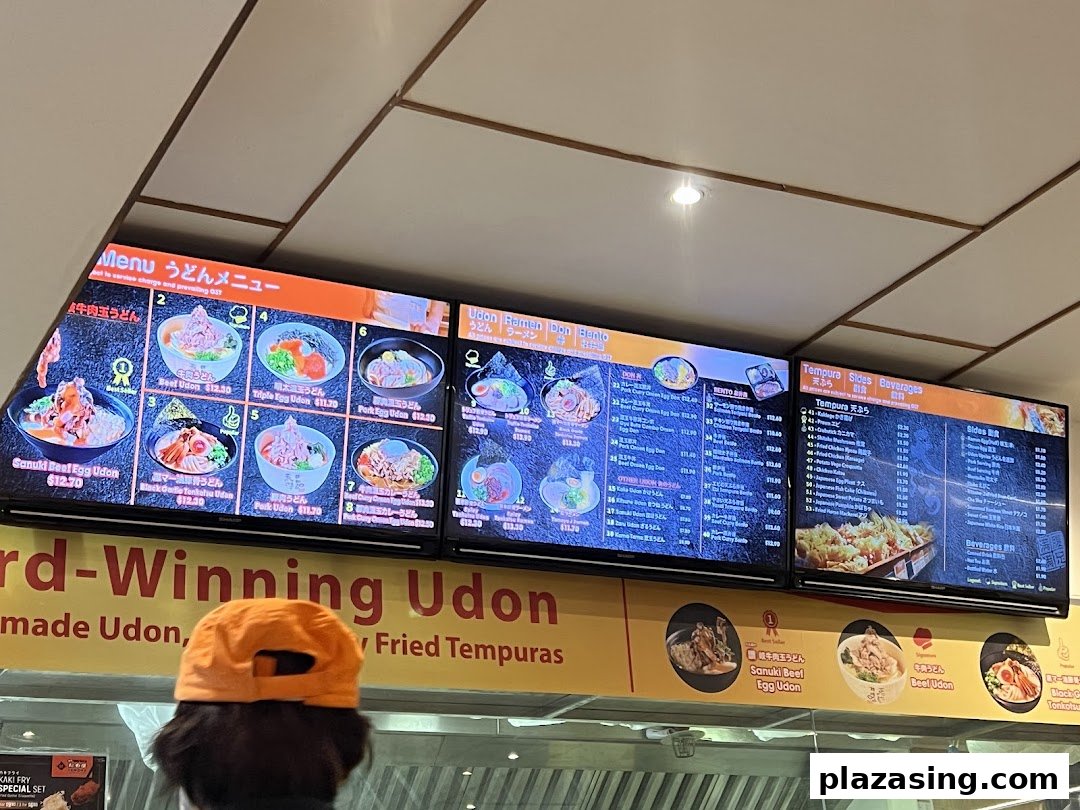 Digital menu boards at Tamoya Udon Tempura, showcasing a variety of udon, ramen, don, tempura, sides, and beverages.