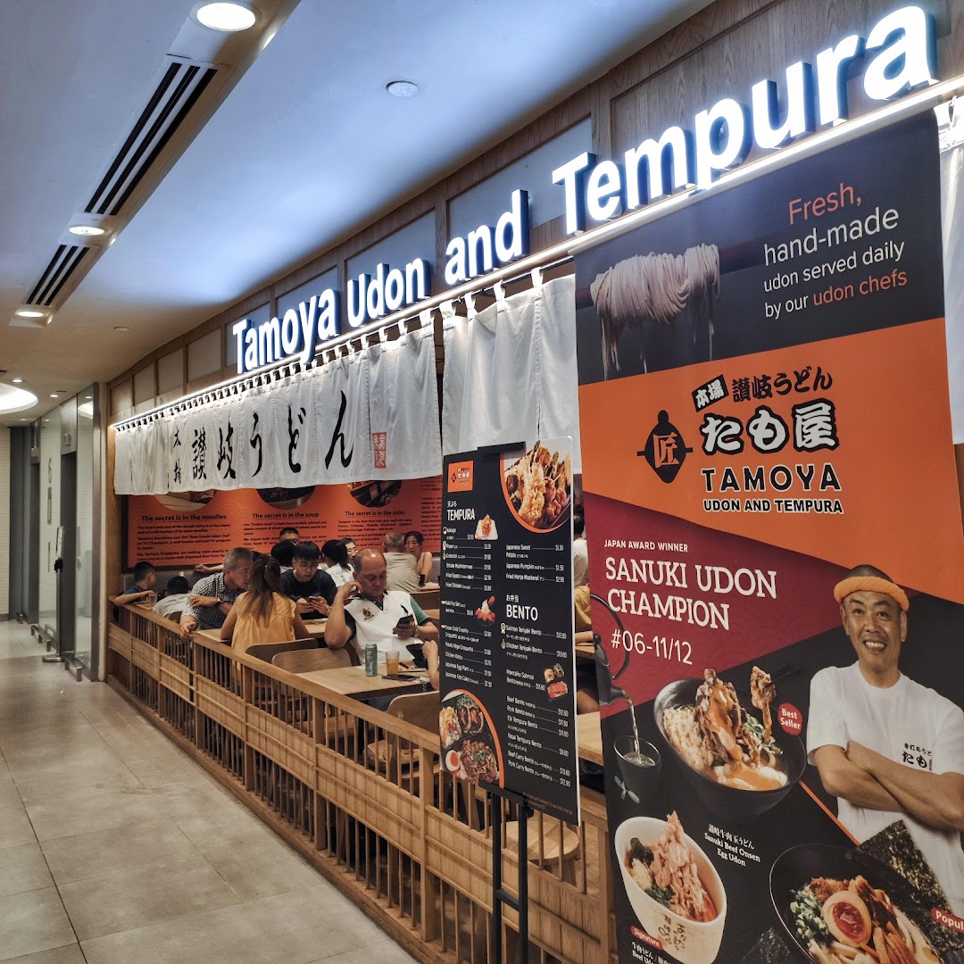 Exterior view of Tamoya Udon and Tempura, showcasing its entrance, seating, and promotional banners.