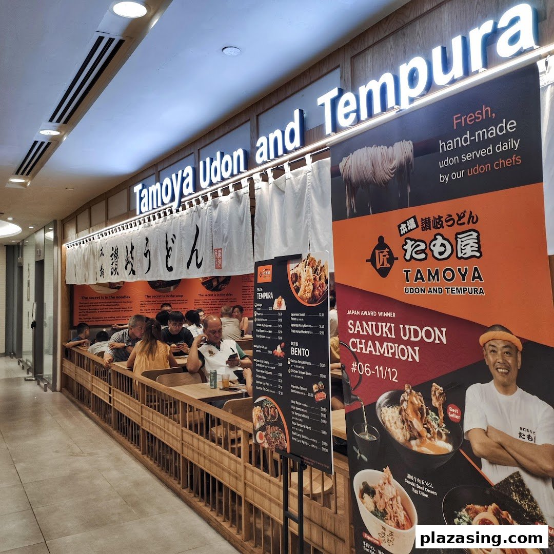 Exterior view of Tamoya Udon and Tempura, showcasing its entrance, seating, and promotional banners.