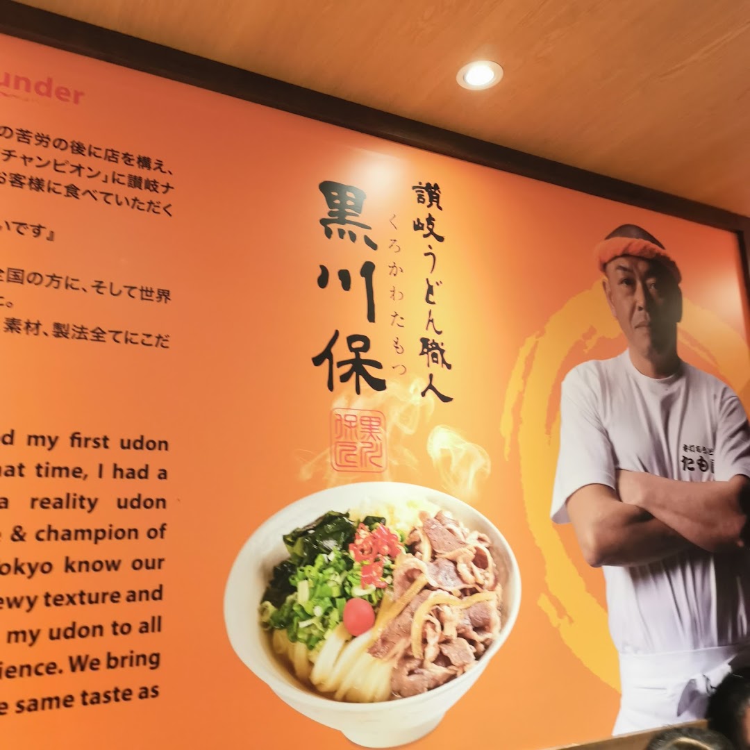 A large wall graphic inside Tamoya Udon featuring a chef, a bowl of udon, and text about the shop's philosophy.