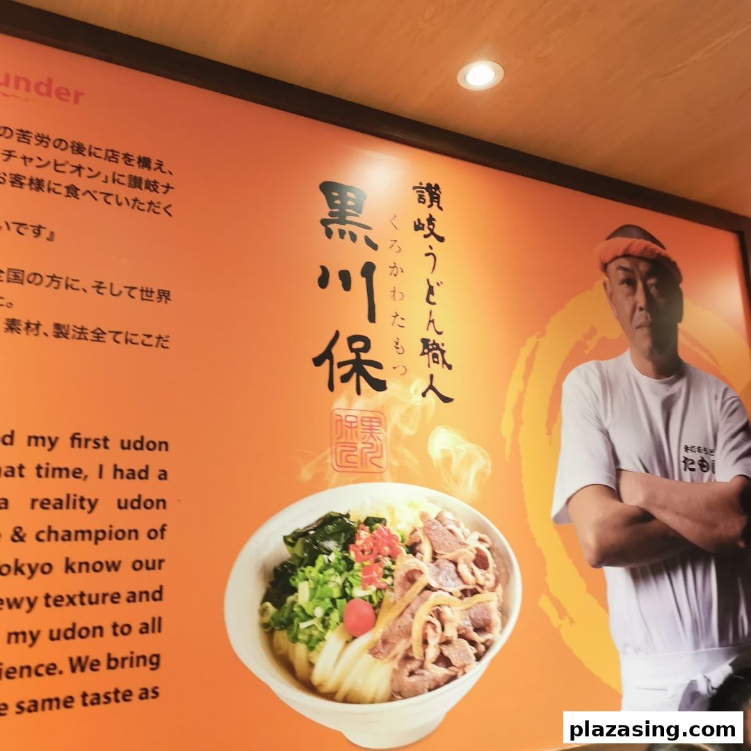 A large wall graphic inside Tamoya Udon featuring a chef, a bowl of udon, and text about the shop's philosophy.