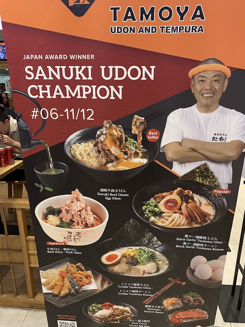 A promotional display board for Tamoya Udon & Tempura, showcasing award-winning udon dishes and other Japanese specialties.