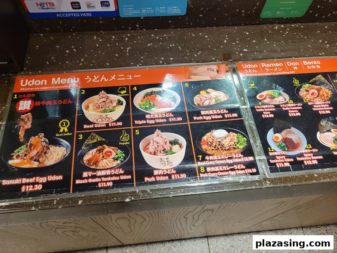 A detailed menu board displaying various udon and ramen dishes with prices and images.