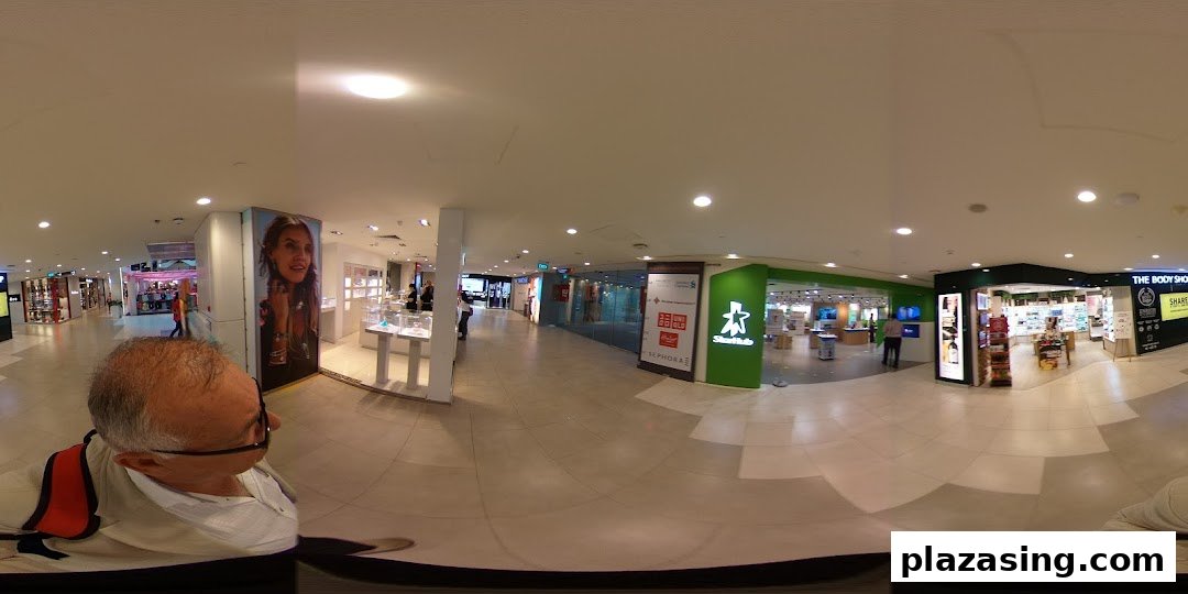 A panoramic view of a brightly lit shopping mall corridor featuring various retail stores, including The Body Shop.