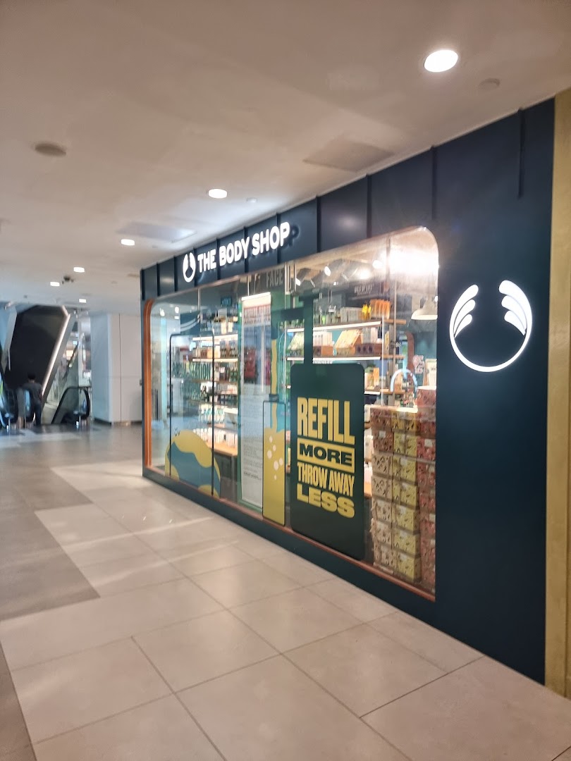 The Body Shop storefront featuring its logo, products, and a 'Refill More Throw Away Less' sign.