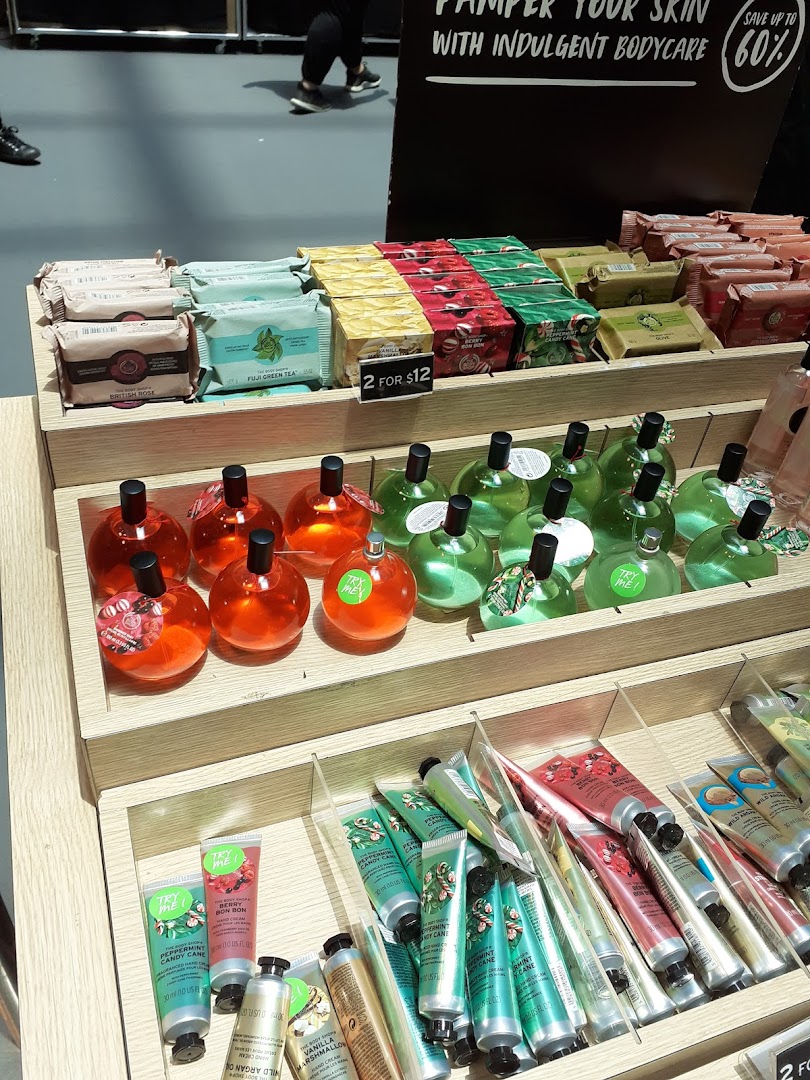 A display of The Body Shop's body care products, including soaps, lotions, and fragrances, with a '2 for $12' offer.