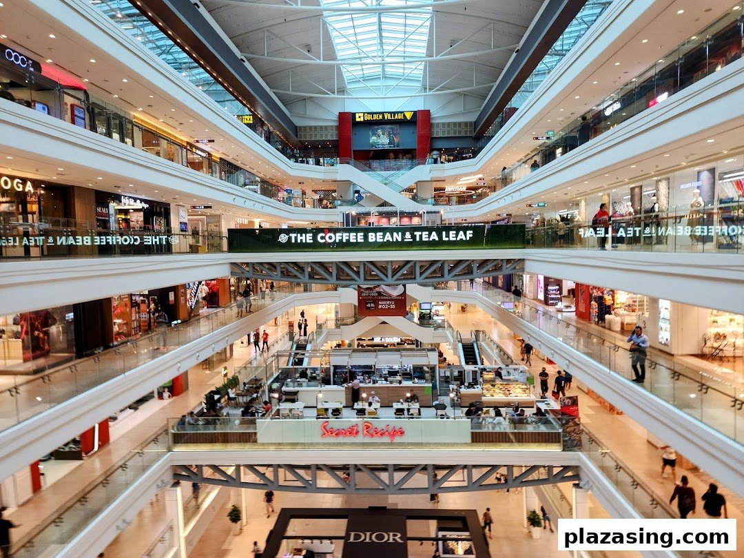 A vibrant multi-level shopping mall interior featuring various retail stores and a prominent 'The Coffee Bean & Tea Leaf' banner.