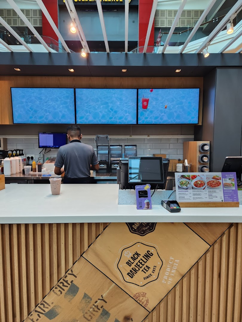 Interior view of The Coffee Bean & Tea Leaf counter with staff and digital displays.