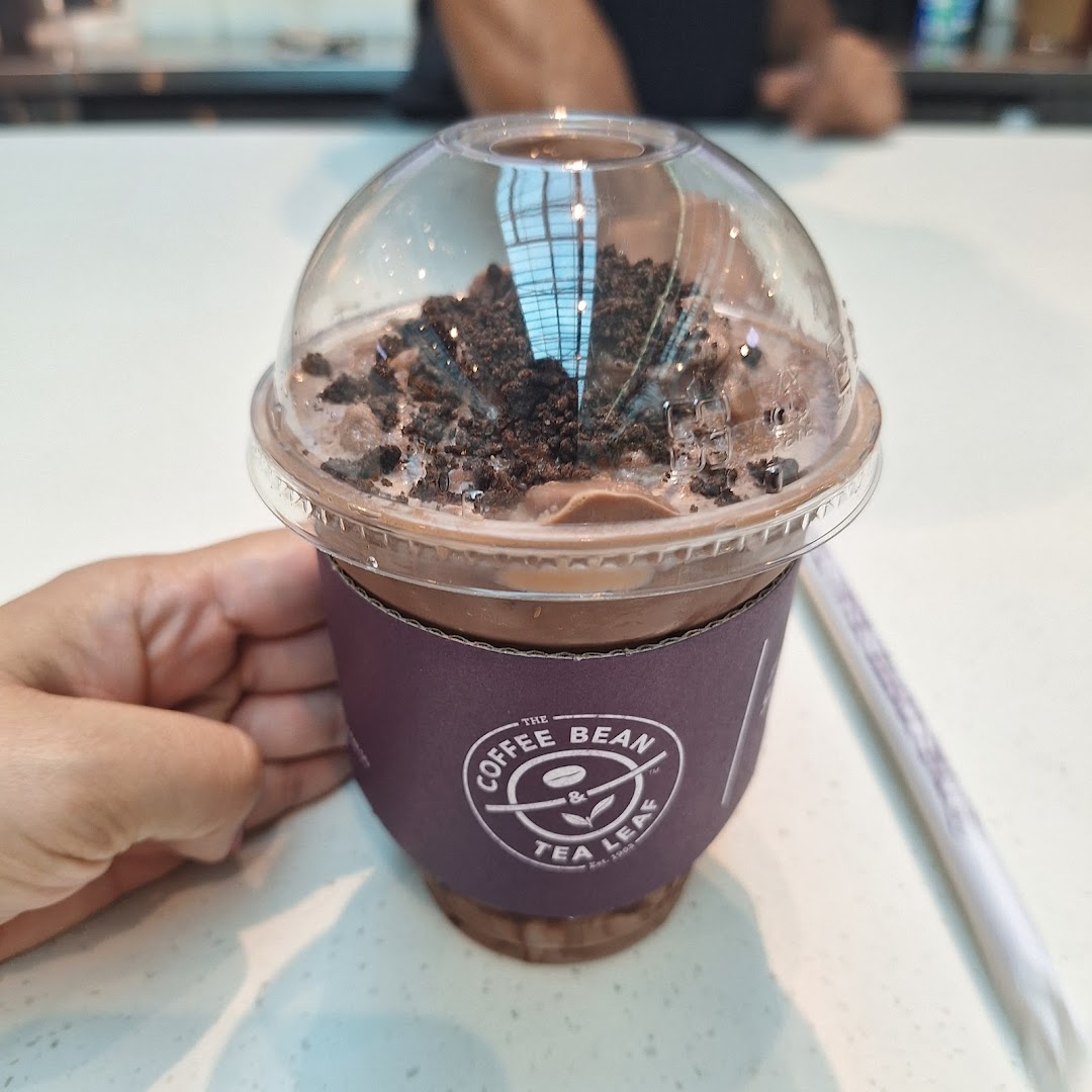 A hand holds a chocolate blended drink topped with cookie crumbs from The Coffee Bean & Tea Leaf.