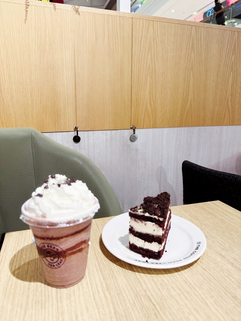 A red velvet cake slice and a chocolate frappe with whipped cream on a wooden table.