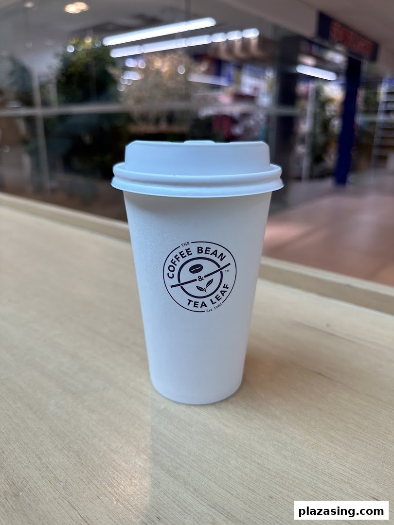 A white coffee cup from The Coffee Bean & Tea Leaf on a wooden surface.