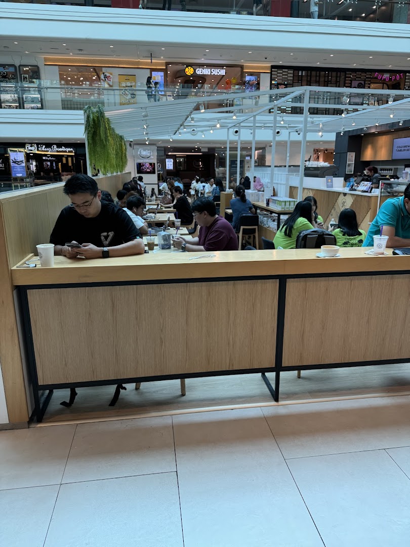 Customers relax and enjoy beverages inside The Coffee Bean & Tea Leaf at a bustling mall.