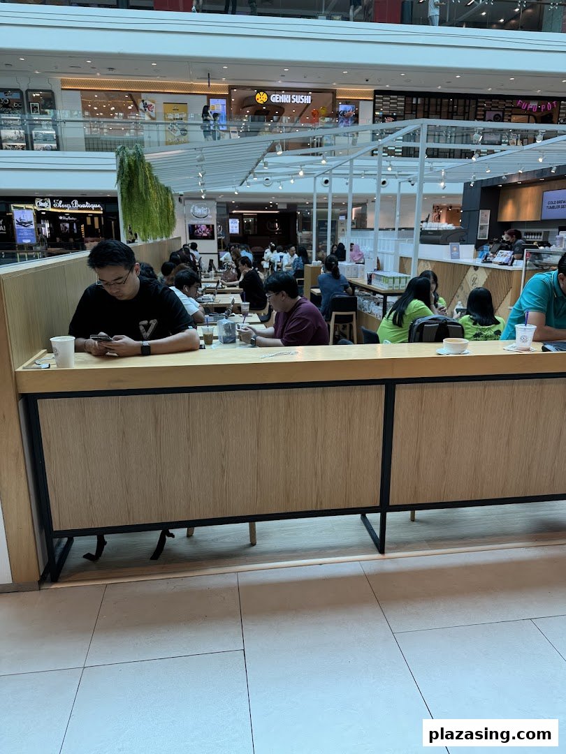 Customers relax and enjoy beverages inside The Coffee Bean & Tea Leaf at a bustling mall.