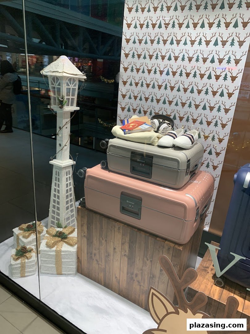A festive holiday window display at The Travel Store featuring luggage, a lamppost, and gift boxes.