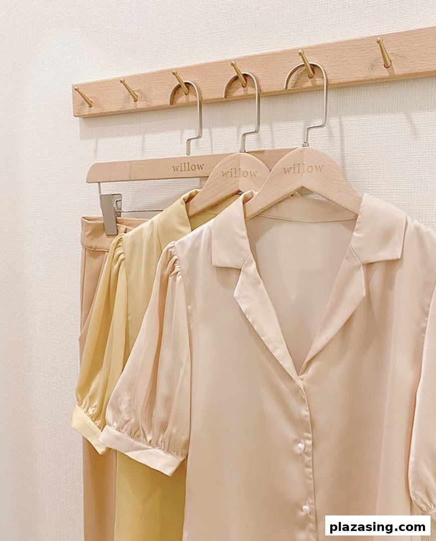 Elegant blouses in soft hues displayed on wooden hangers at The Willow Label.