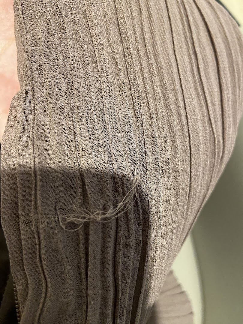 Close-up of a pleated fabric garment, highlighting its texture and detail.