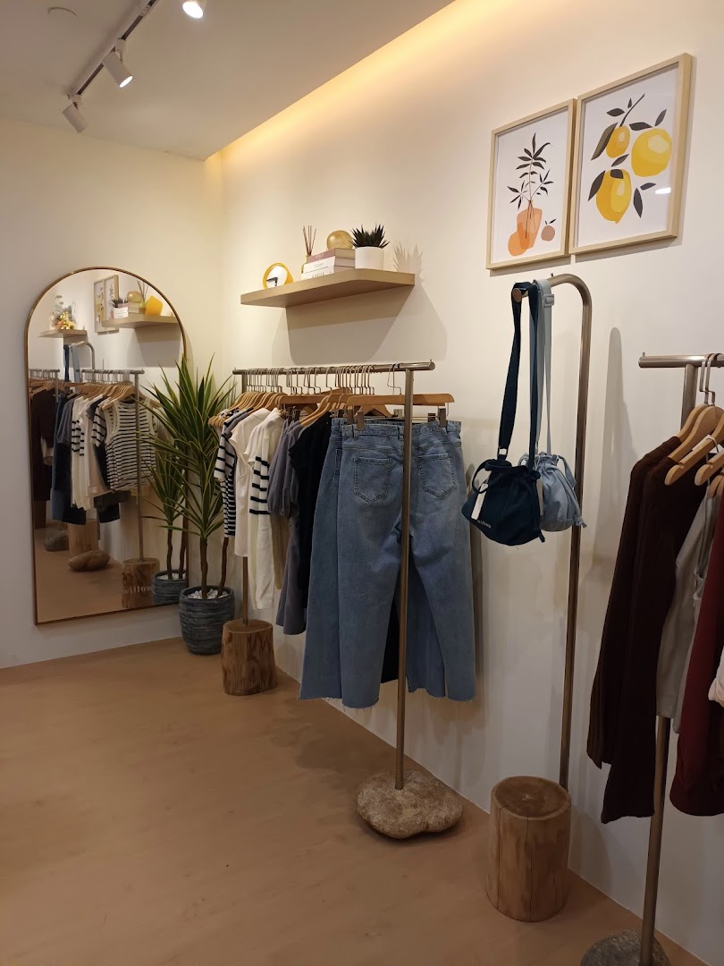 Interior view of The Willow Label, showcasing stylish apparel, a large mirror, and minimalist decor.