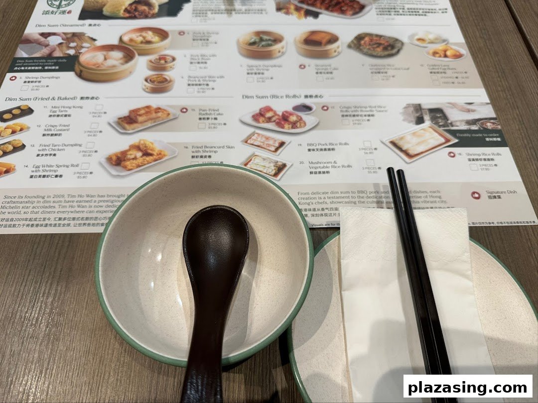 A close-up of Tim Ho Wan's dim sum menu, showing various dishes, prices, and a table setting.