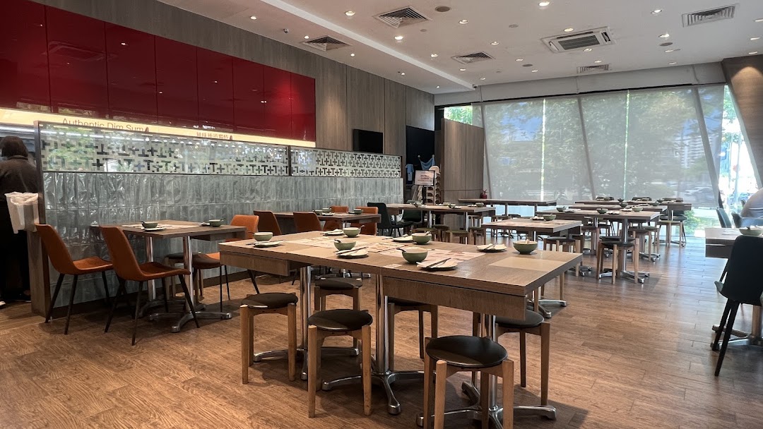 Spacious and modern dining area of Tim Ho Wan, set with tables and chairs for guests.