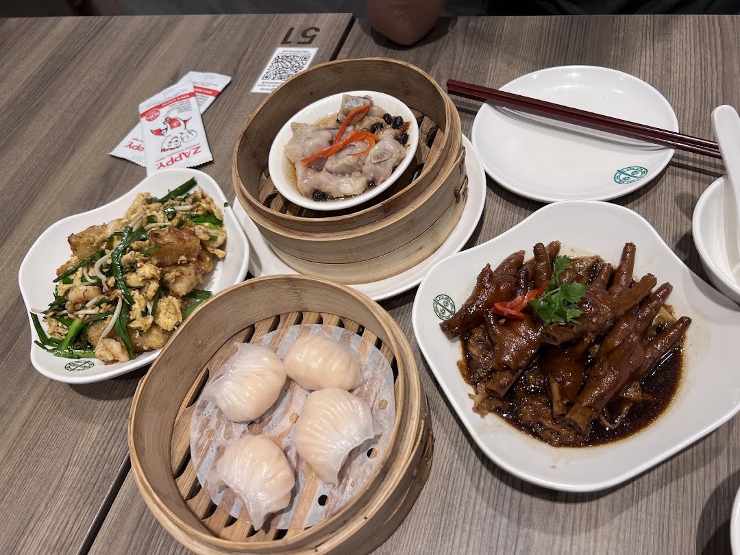 A table laden with various delicious dim sum dishes, including har gow, chicken feet, and stir-fried radish cake.