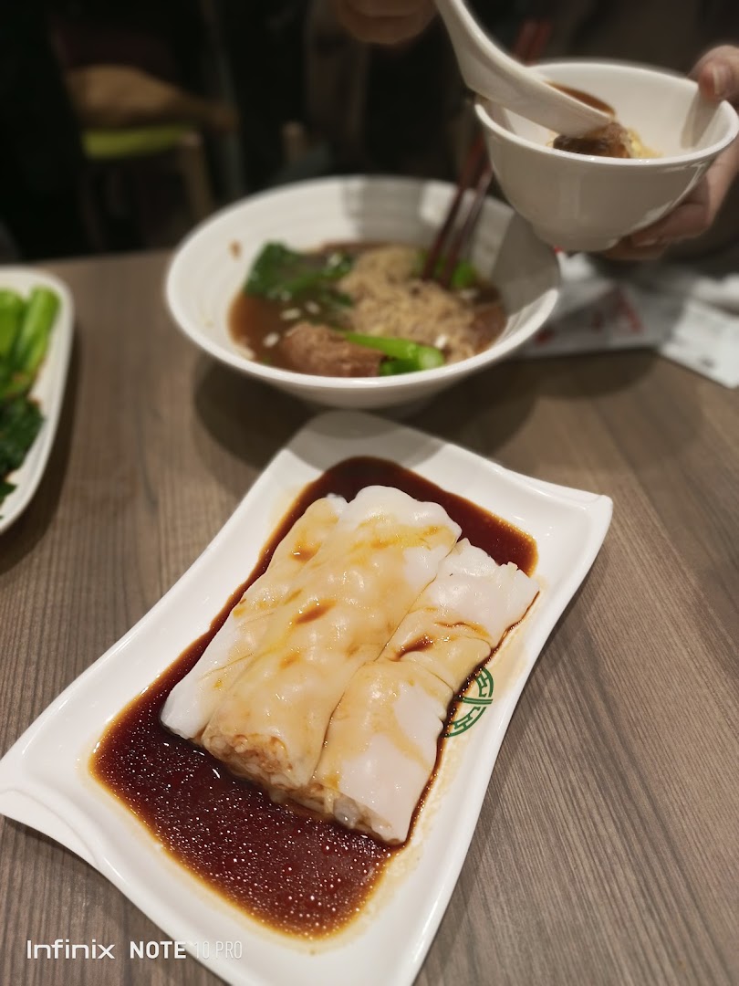 Delicious rice rolls with sauce in the foreground, with a bowl of noodles and vegetables in the background.