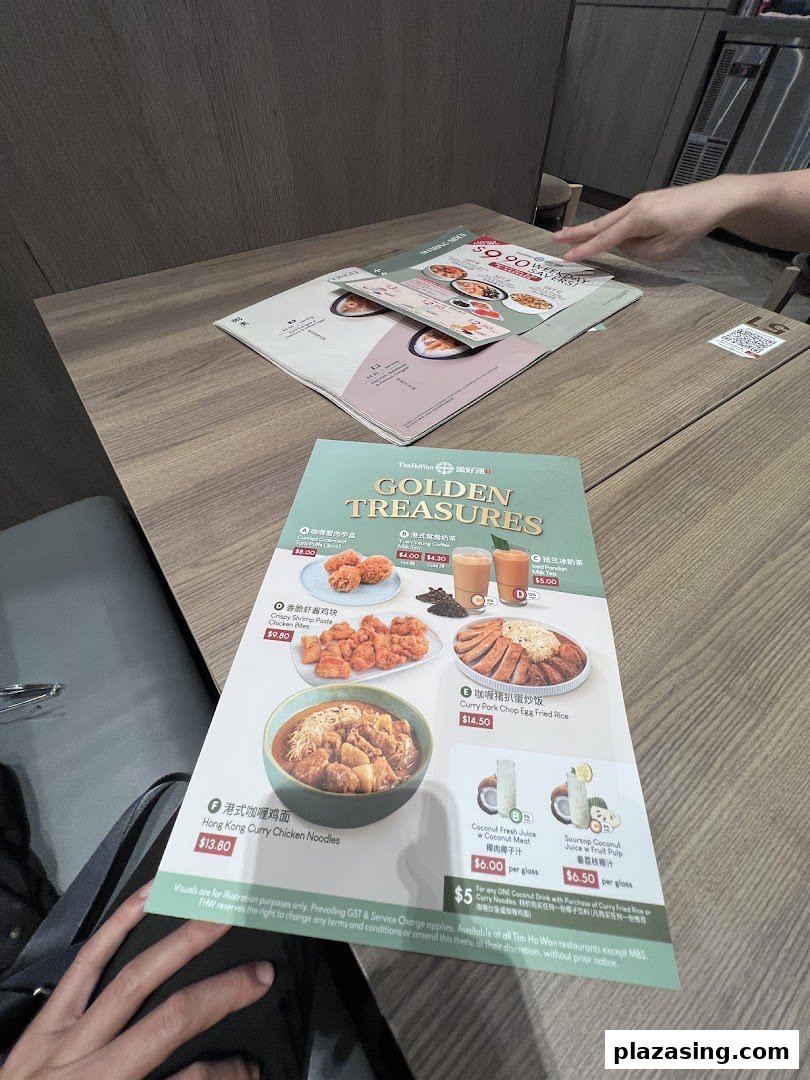 A close-up of a Tim Ho Wan menu displaying various dishes and drinks on a wooden table.