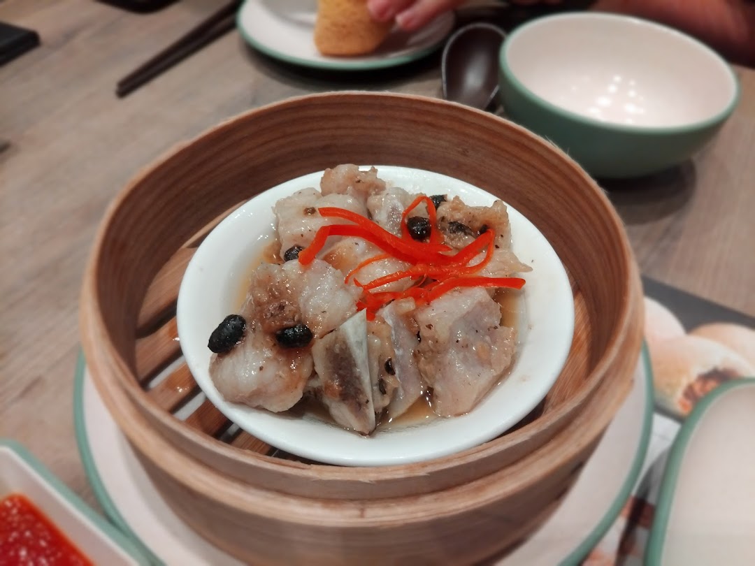 A close-up of steamed pork ribs with black beans and chili, served in a traditional bamboo steamer.