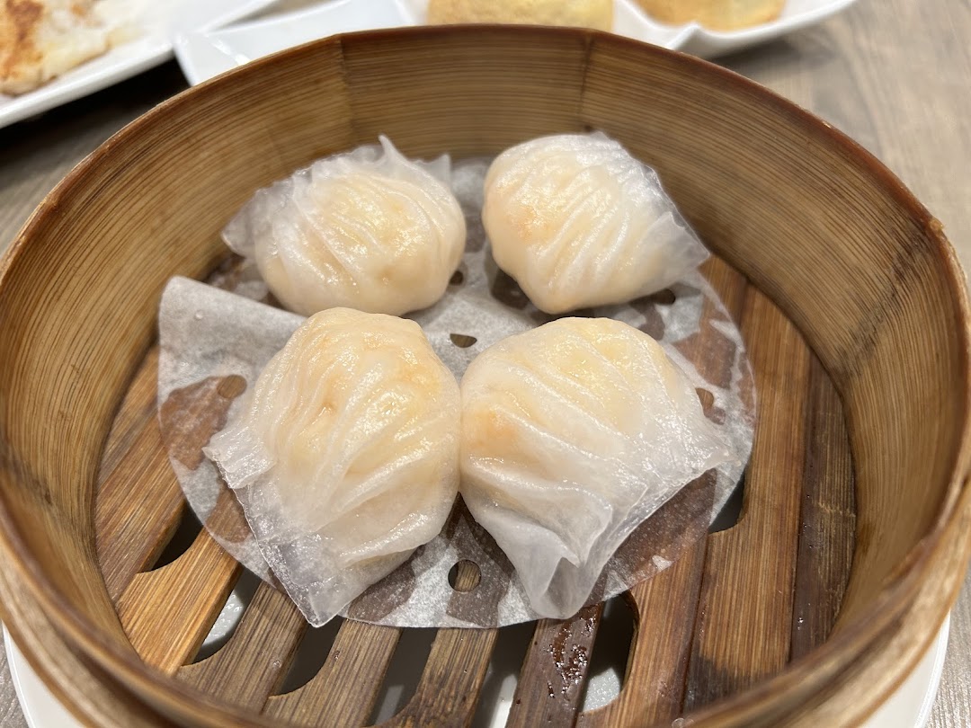 Four perfectly steamed shrimp dumplings (har gow) presented in a traditional bamboo steamer.