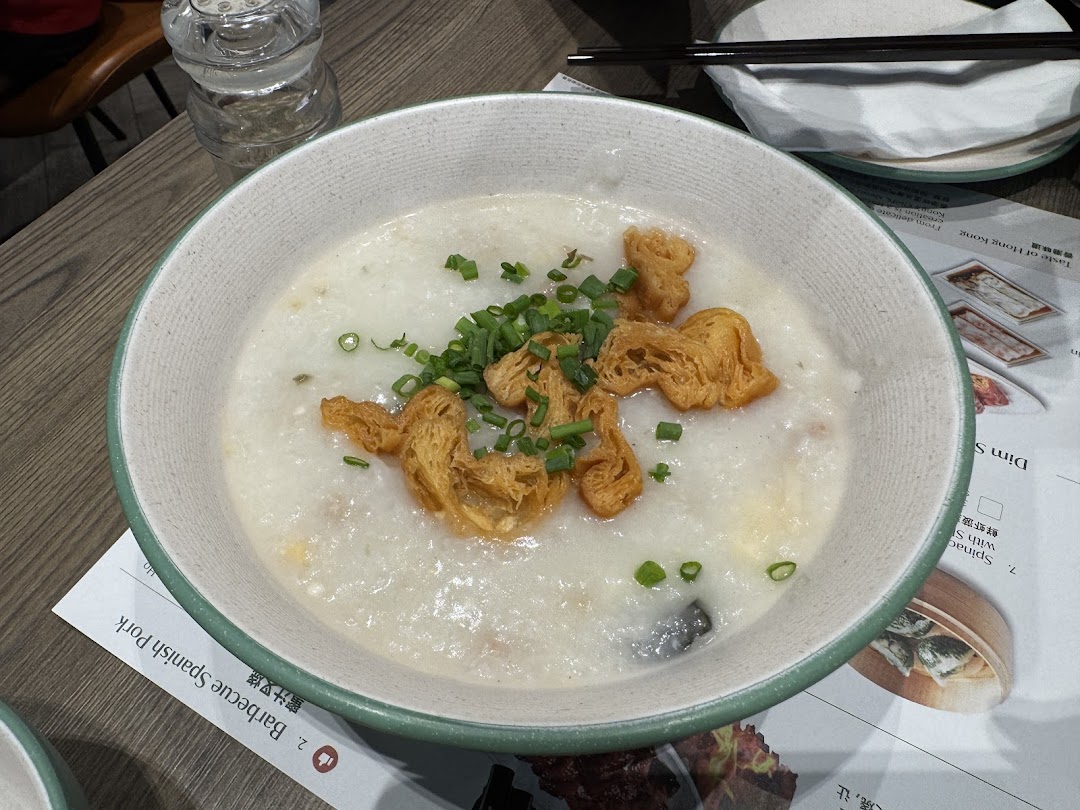 A comforting bowl of congee topped with crispy fried dough and fresh spring onions.