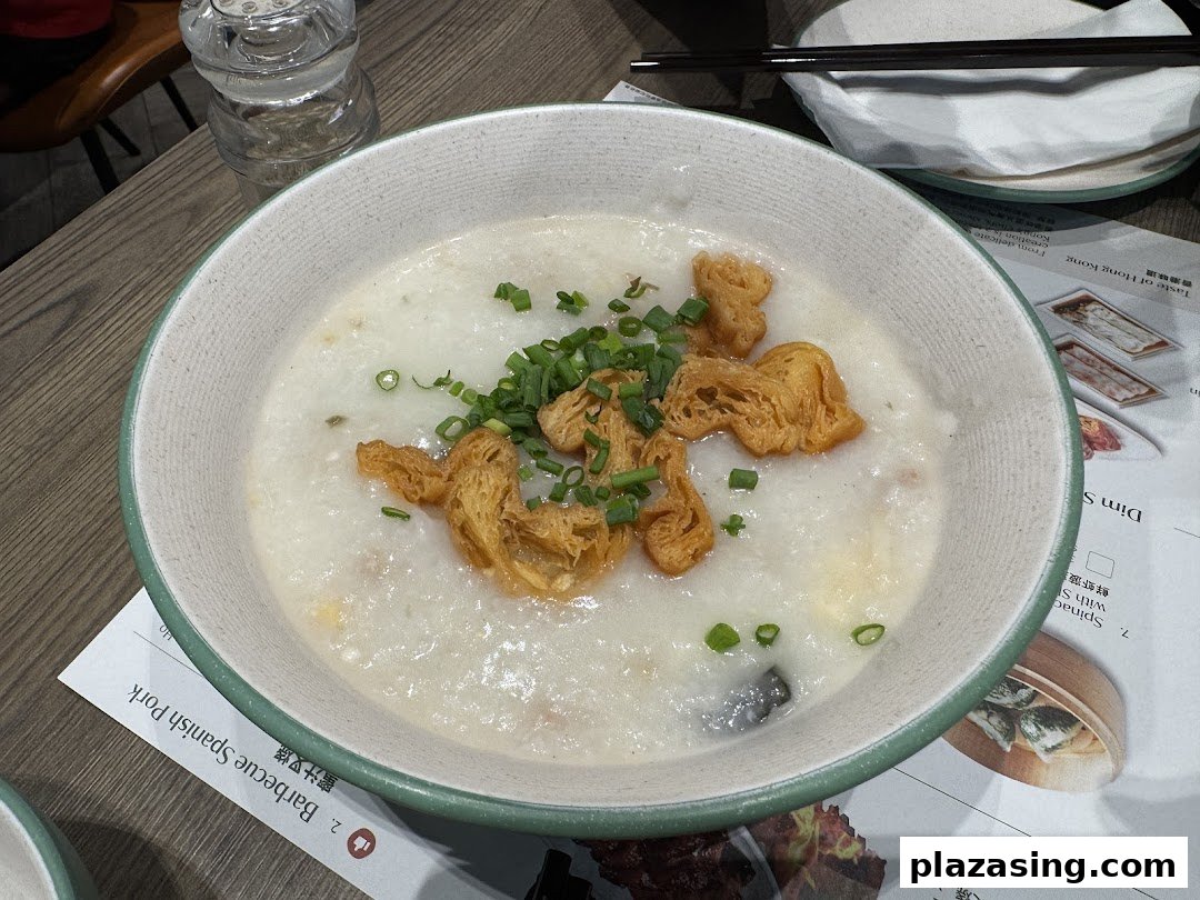 A comforting bowl of congee topped with crispy fried dough and fresh spring onions.