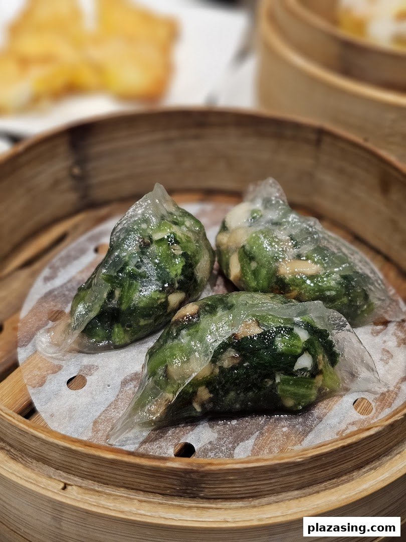 Three vibrant green vegetable dumplings steamed to perfection in a traditional bamboo basket.