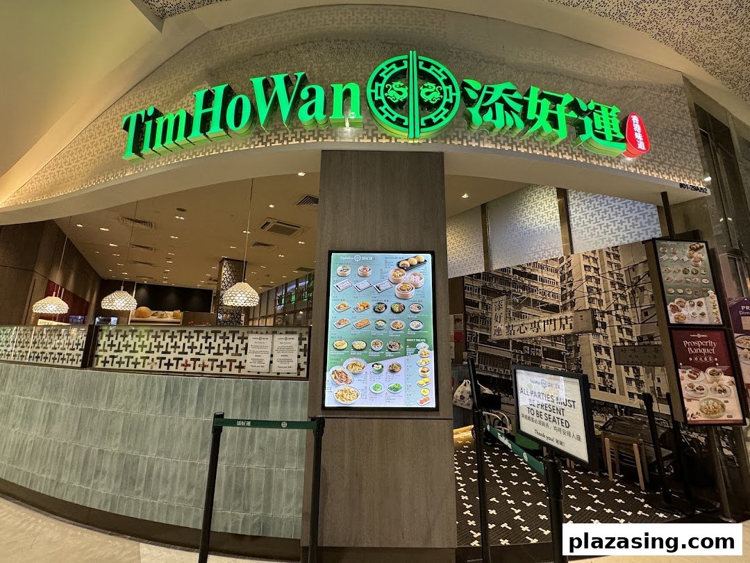 The exterior of Tim Ho Wan, a dim sum restaurant, featuring its vibrant green signage and a digital menu display.