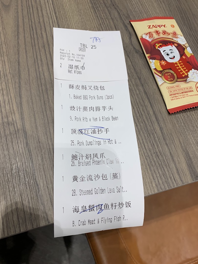 A close-up of a Tim Ho Wan order receipt listing various dim sum items and a wet wipe packet.