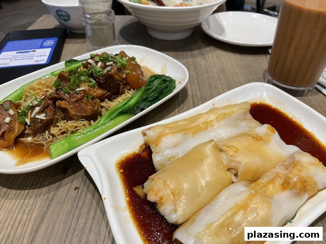 Delicious Tim Ho Wan dishes: braised beef noodles, rice rolls, and a refreshing drink on a table.
